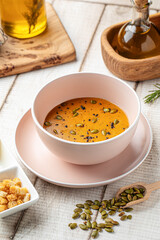 Warm lentil soup served with pumpkin seeds, lemon slice and crispy croutons on wooden table