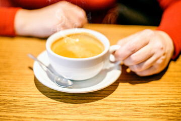 A girl drinks coffee at a table in a cafe
