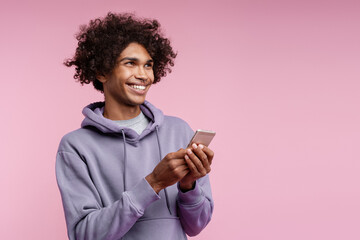 Smiling happy African American man holding mobile phone using mobile app text message looking away