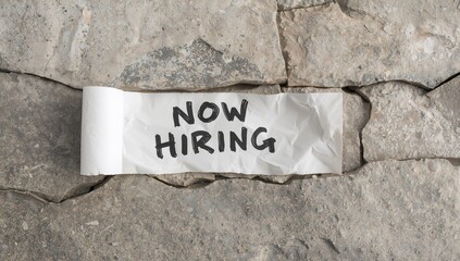 Now hiring message on torn paper with a stone backdrop, emphasizing recruitment urgency