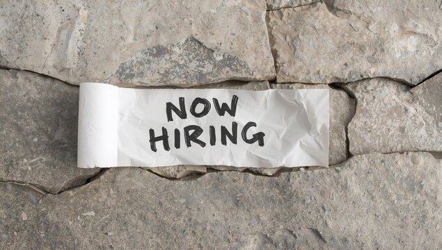 Now hiring message on torn paper with a stone backdrop, emphasizing recruitment urgency