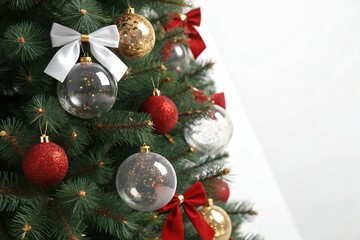 Festive Christmas tree adorned with shiny ornaments and bows, ready for holiday celebrations.
