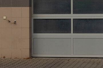 closed service bay with wall sensors and tiled facade, subtle utility fixtures and neutral pavement indicate