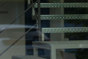 Glass showcases functional stair structure, Metal fire escape visible through clear glass panels, Architectural metal staircase with safety handrails contrasts with corporate frontage