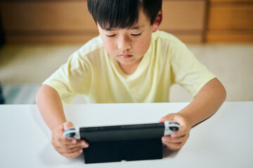 Naklejka premium 家庭用ゲーム機でゲームをする小学生の男の子