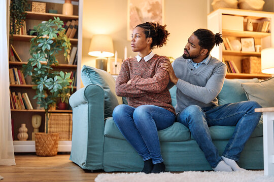 Porrait of a husband comforting wife embrace and showing support. Woman upset man, expressing sympathy and understanding, sitting on sofa at home.