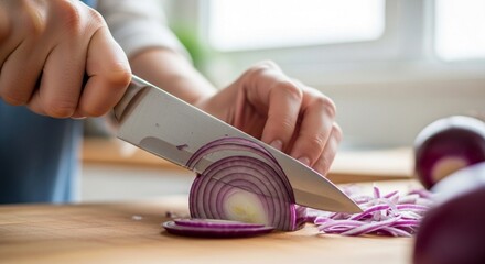 Close-up of hands slicing a red onion on a wooden cutting board with a sharp knife.