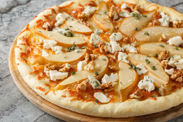 Honey pear pizza with blue cheese, nuts, mozzarella and thyme close-up on a wooden board on the table. Horizontal