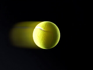 Fast tennis ball in motion with yellow trail on black background