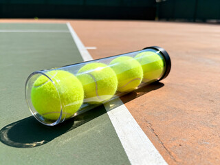 Tennis ball tube lying on hard court under midday sun