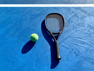 Tennis racket with ball on bright blue hard court surface