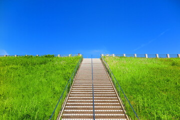 快晴の青空と緑の草が生い茂る堤体の歩道の風景14