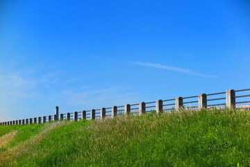 快晴の青空と緑の草が生い茂る堤体の歩道の風景1