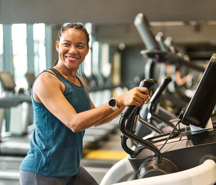 Portrait of a young black woman exercising on an elliptical trainer in a gym, running using  thereadmill machine equipment, healthy lifestyle and cardio exercise at fitness club concepts
