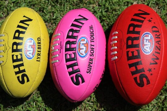 Yellow, pink and red AFL footballs