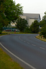 Fototapeta premium The photograph features a blurred image of a winding road, with a building visible in the distant background, creating an intriguing scene