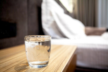 Glass of water on a bedside table in a cozy bedroom, symbolizing hydration, wellness, and post-workout recovery in a calm self-care setting.