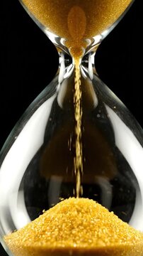 Hourglass with golden sand flowing, dark background, close-up view