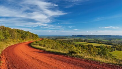 Red dirt road surrounded by trees and green fields, seasonal change
