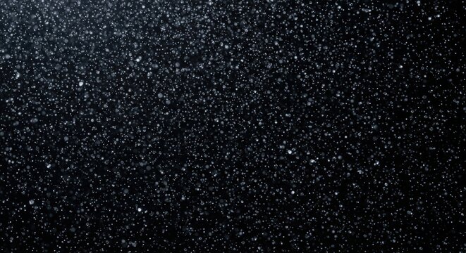 A close-up, high-contrast shot of a dark, textured surface with tiny, sparkling particles scattered across it.