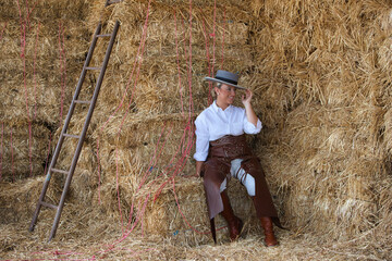 A young, attractive woman riding a horse, dressed in riding clothes and a traditional Spanish hat,...