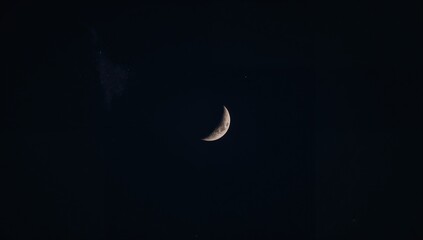 A photograph featuring a crescent moon, capturing the beauty of nighttime illumination