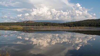 Reflection of white storm clouds on the surface of an estuary, erosion risk