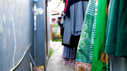 Naklejka premium Row of colorful clothes hanging outside under a metal roof, drying in daylight.