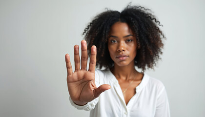 African American woman raises hand in stop gesture. Female shows hand in denial on white background. Black person protesting domestic violence. Fight against discrimination. Stop sign