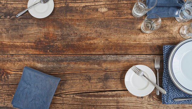 Table setting featuring cutlery and an empty plate on a wooden surface, suitable for editorial layout