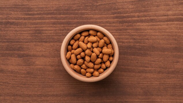 Bowl of unshelled peanuts on rustic wood surface, nutritious snack option
