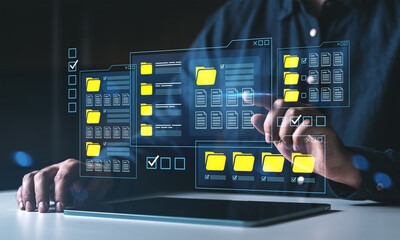 Man using futuristic digital interface with file folders and documents on transparent screen above tablet, representing data management concept.
