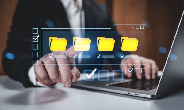 Businessman interacting with digital file folders on touchscreen interface, futuristic data management concept on office background.