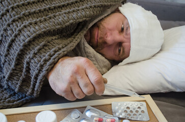 A man with a bandage on his head lies in bed. The concept of illness, cold, acute respiratory viral infection.