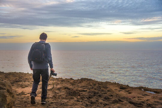 Nature photographer walking on a rocky coast - Powered by Adobe