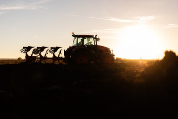 Tractor plowing field the land at sunset