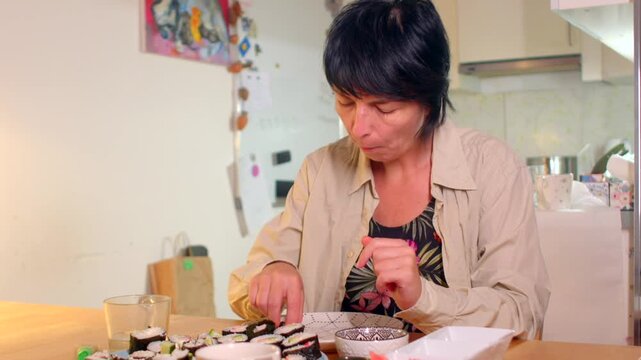 Caucasian woman reviews sushi pieces in kitchen, Woman of Caucasian descent evaluates sushi rolls under bright light