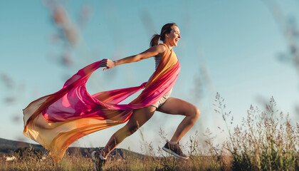 Joyful woman running in open field with colorful flowing fabric summer sunlight happiness freedom outdoor activity energetic movement clear blue sky nature background