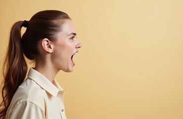 Young woman shouts with open mouth and wide eyes. Her side profile shows strong emotion. She wears a simple collared shirt against a plain beige backdrop.