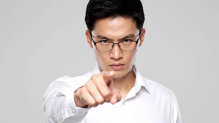 Serious asian man with an angry expression pointing his index finger at the camera. Concept of blame, accusation, and getting fired