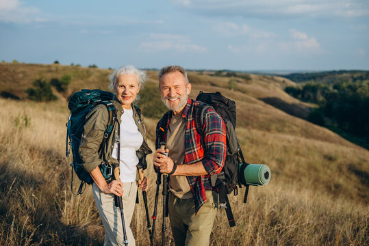 Smiling hikers pose after Nordic walking ascent on hill top
 - Powered by Adobe