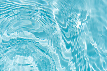 Blue water with ripples on the surface. Defocus blurred transparent blue colored clear calm water surface texture with splashes and bubbles. Water waves with shining pattern texture background.