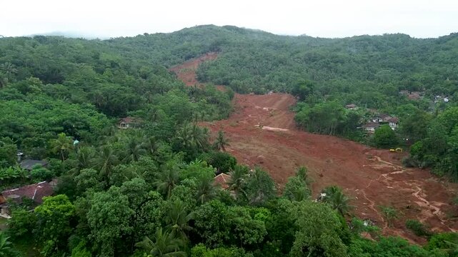 Landslide aerial view of severe scar on green hilly landscape. Suitable for disaster, geological, landscape, and environmental concepts.