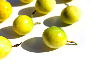 Yellow passion fruits on a white surface with shadows