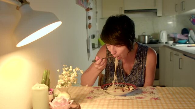 caucasian woman tasting food at small table lamp glow thoughtful expression evaluating flavor intimate kitchen scene