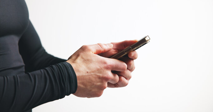 Phone, hands and man in studio with fitness research, mobile app or workout plan for training. Technology, networking and male athlete with cellphone for sports communication by white background.