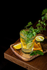 A vibrant cocktail sits on a wooden tray, surrounded by fresh mint and citrus slices. The drink glistens with ice, capturing the essence of summer relaxation moments