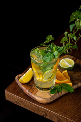 A vibrant mojito sits on a polished wooden surface, surrounded by fresh mint leaves and colorful citrus slices. This refreshing drink highlights a perfect summer afternoon atmosphere