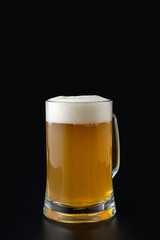 A clear glass mug filled with golden beer sits on a dark surface. The frothy white head spills slightly over the rim, inviting enjoyment during social moments or relaxing evenings
