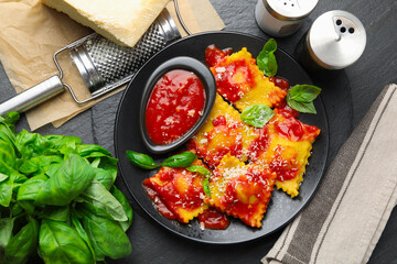 Delicious ravioli with tomato sauce, cheese, grater and basil on grey table, flat lay